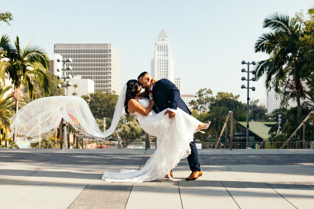 Bride and Groom kissing with veil blowing in the wind in front of Los Angeles City Hall