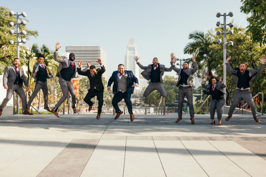Groomsmen jumping in unison in front of Los Angeles City Hall