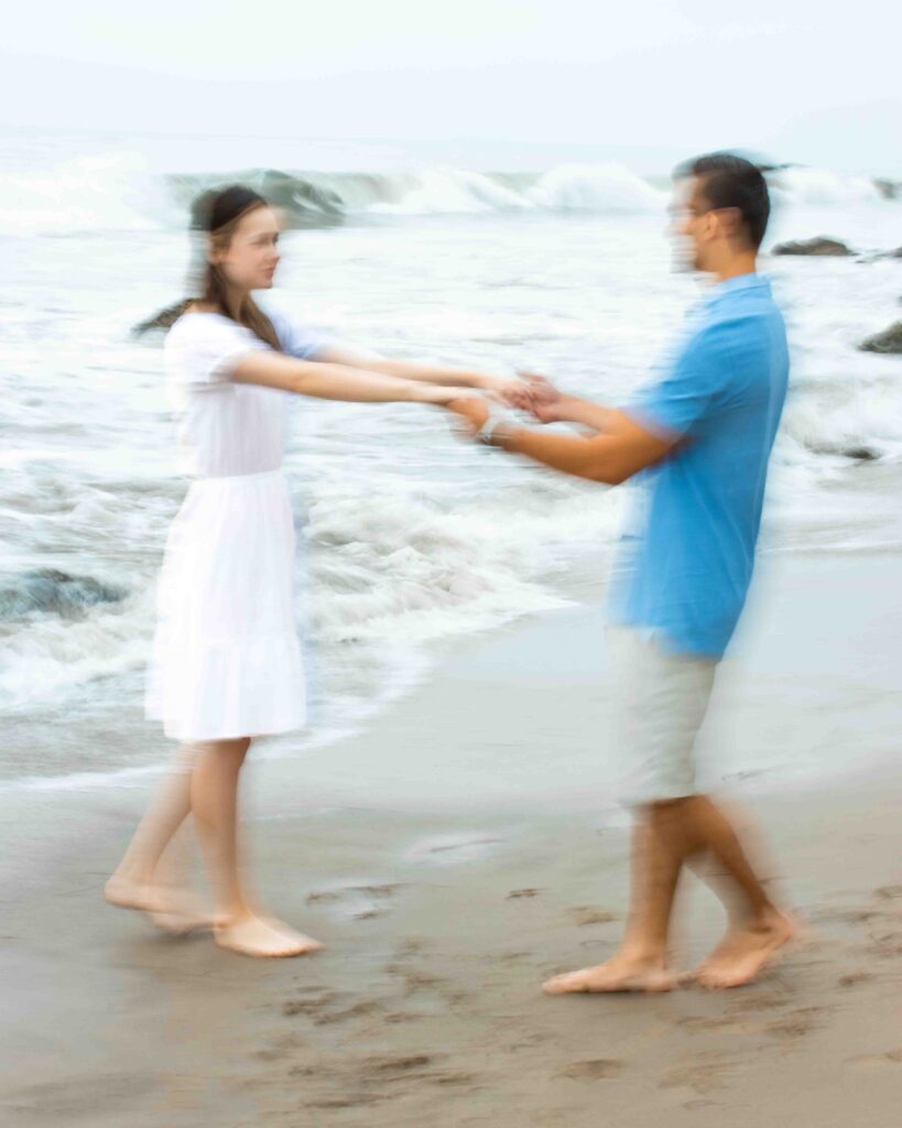 Motion blurred image of a couple spinning around each other on a cloudy beach